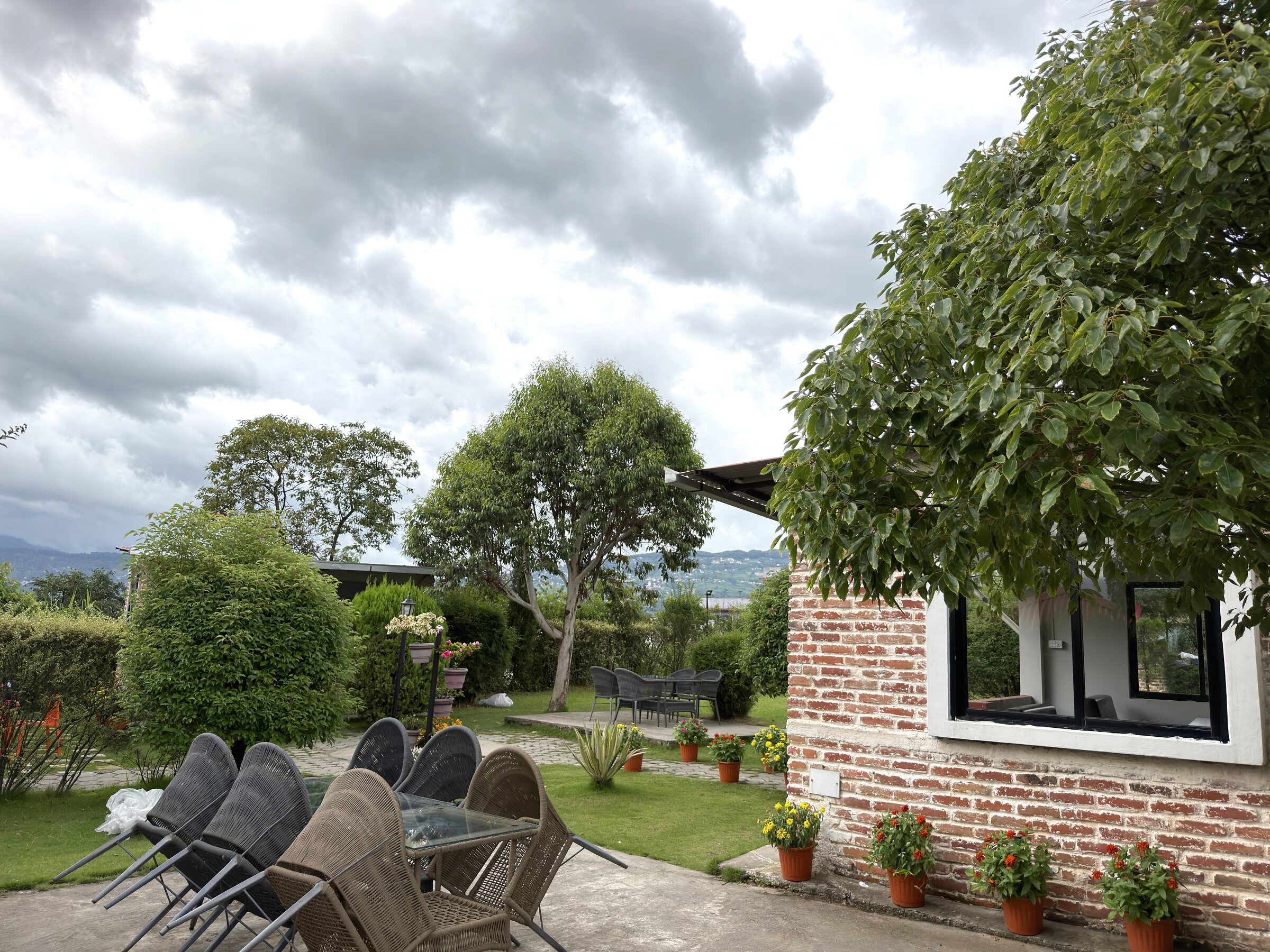 Garden seating area beside a brick pavilion with a lawn and distant valley view