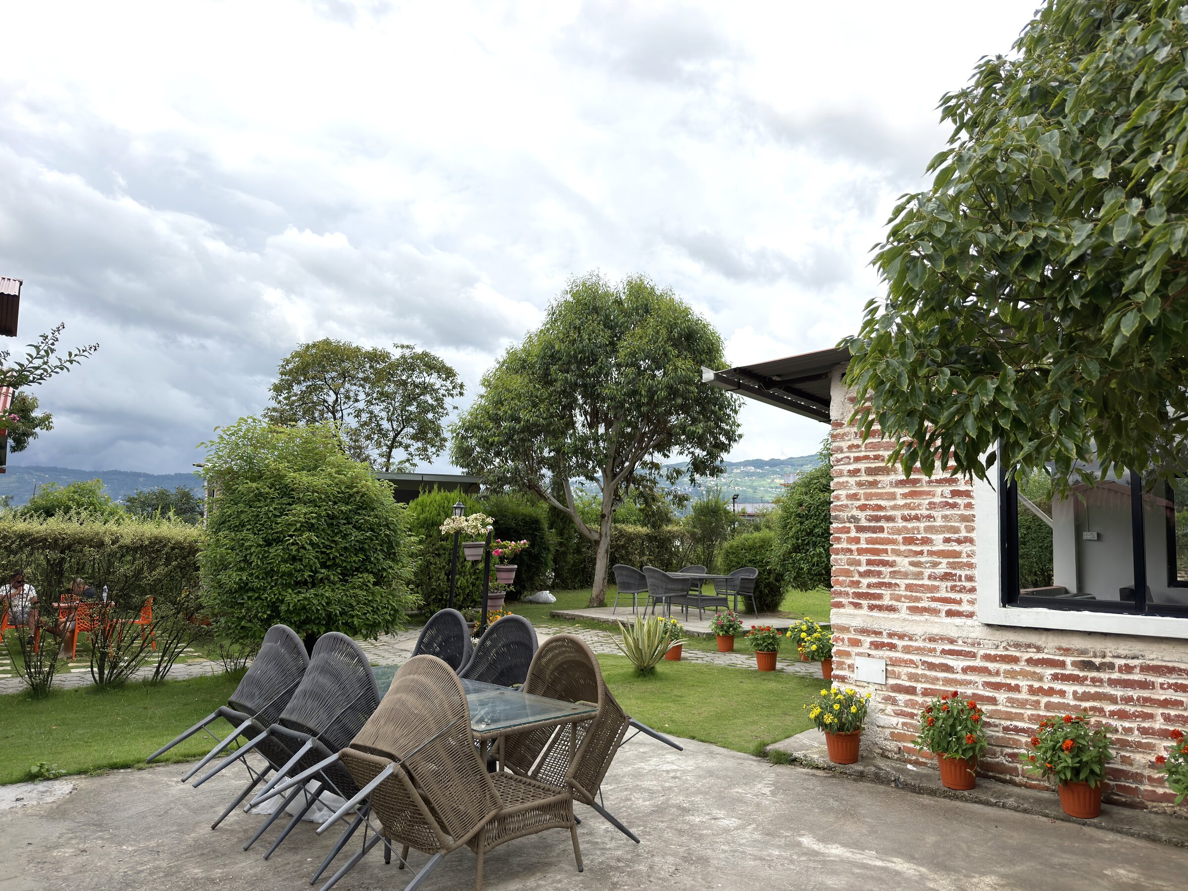 Outdoor dining table and wicker chairs on the patio beside the brick guest house