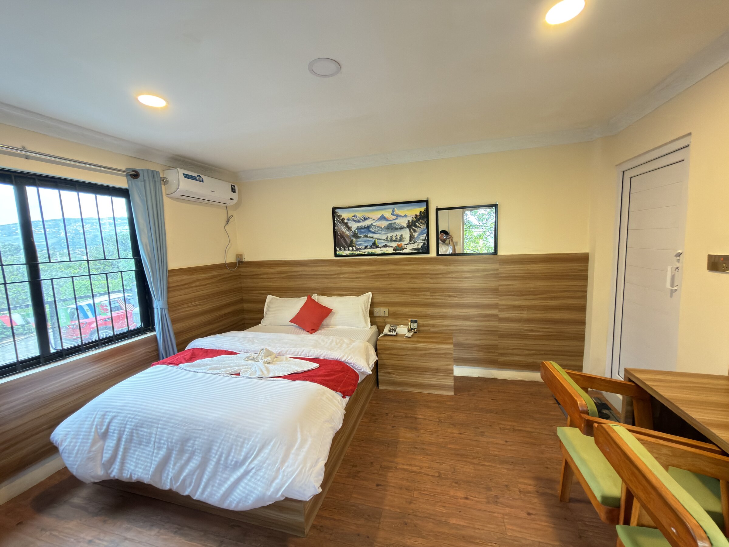 Double room with dressed bed, garden-view window and wood-panelled headboard