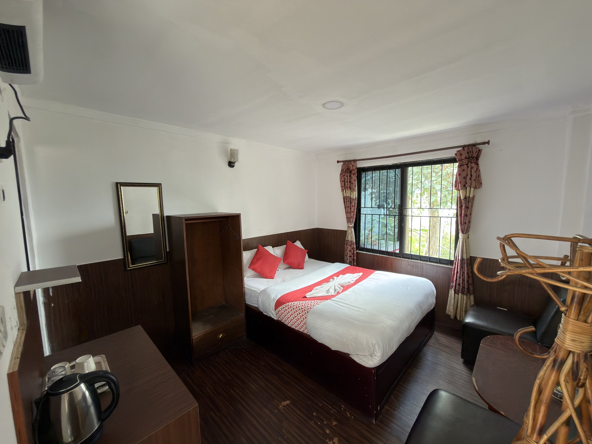 Double room with red accent pillows and a garden-facing window