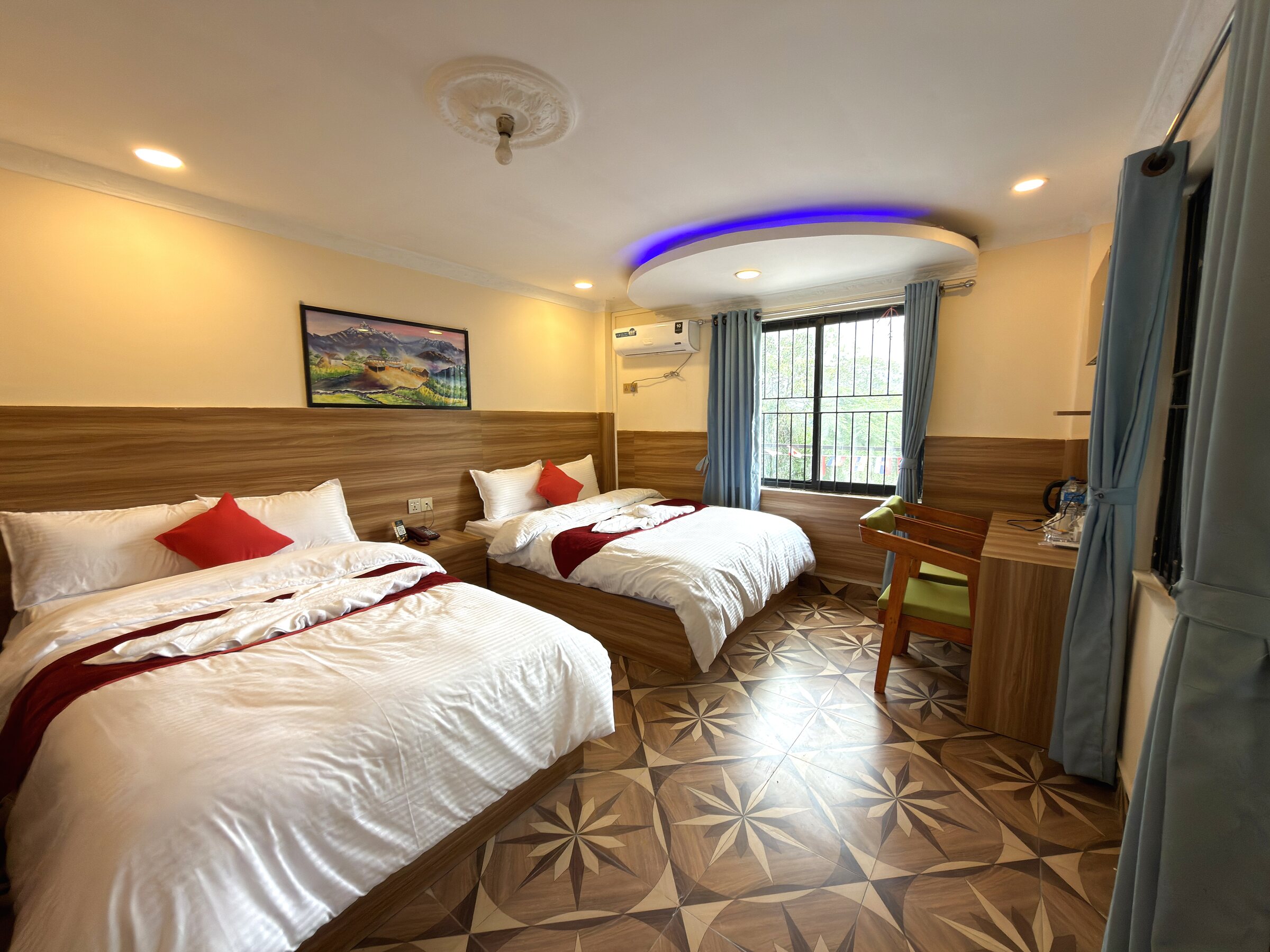 Twin hotel room at White Orchid Resort with wood-panelled headboard, patterned wood floor and garden-facing window